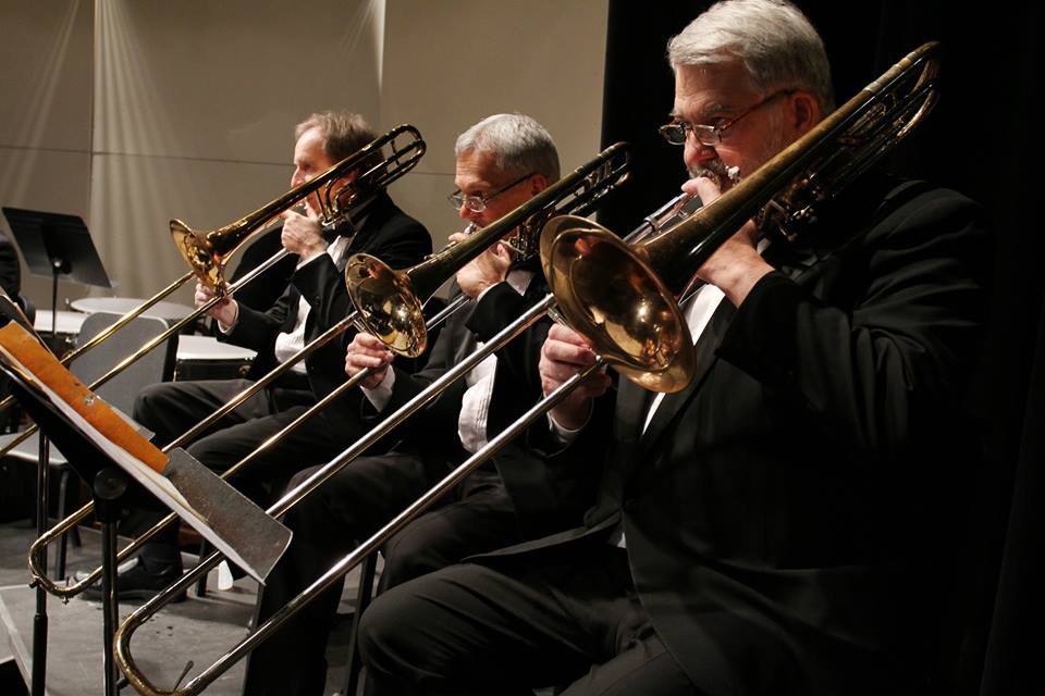 Musicians play trombones in orchestra