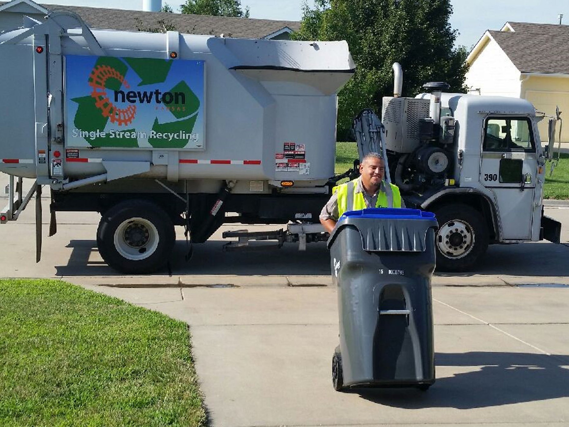 City employee rolling a recycling cart