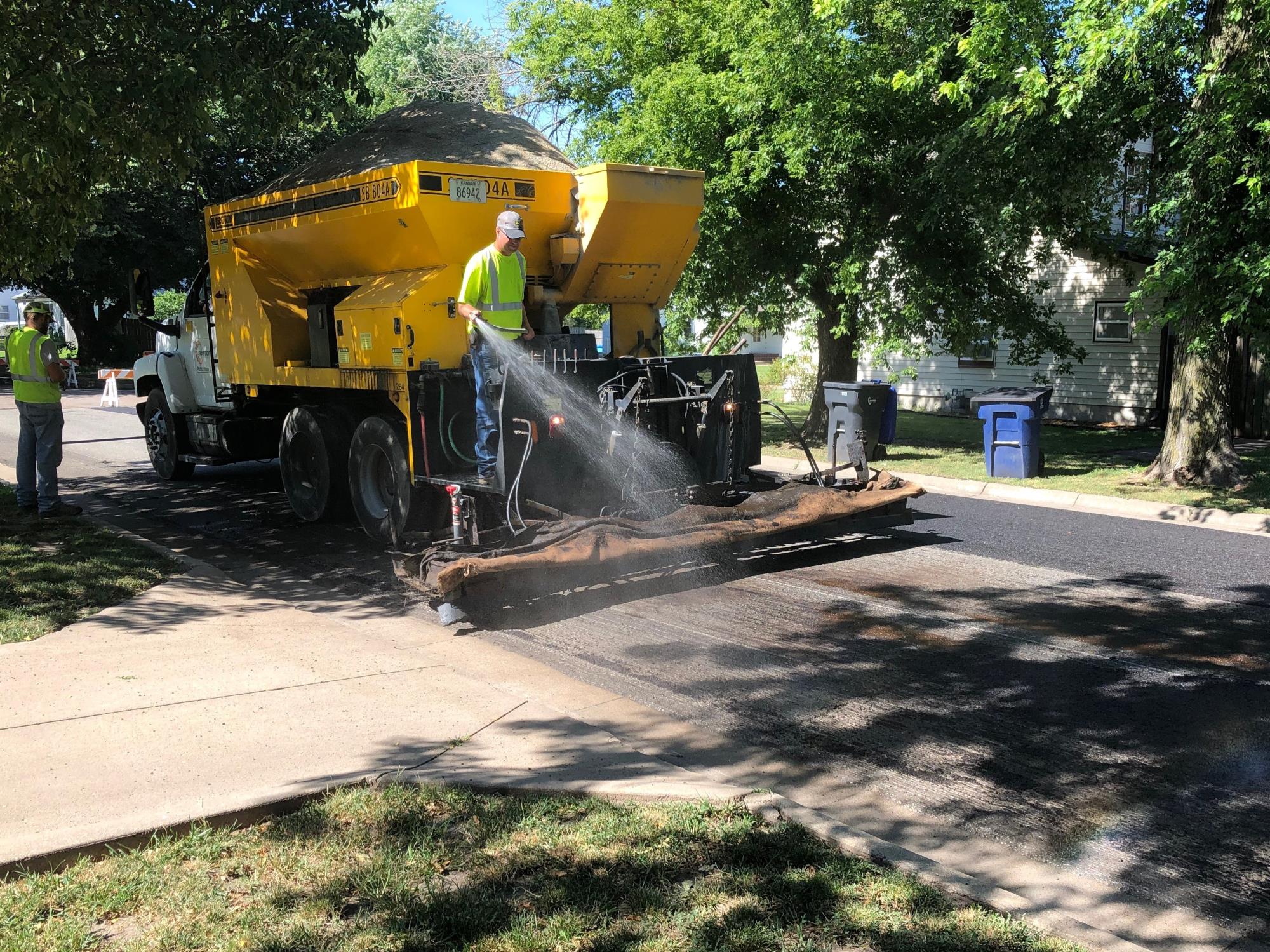 City employees applying slurry seal to street