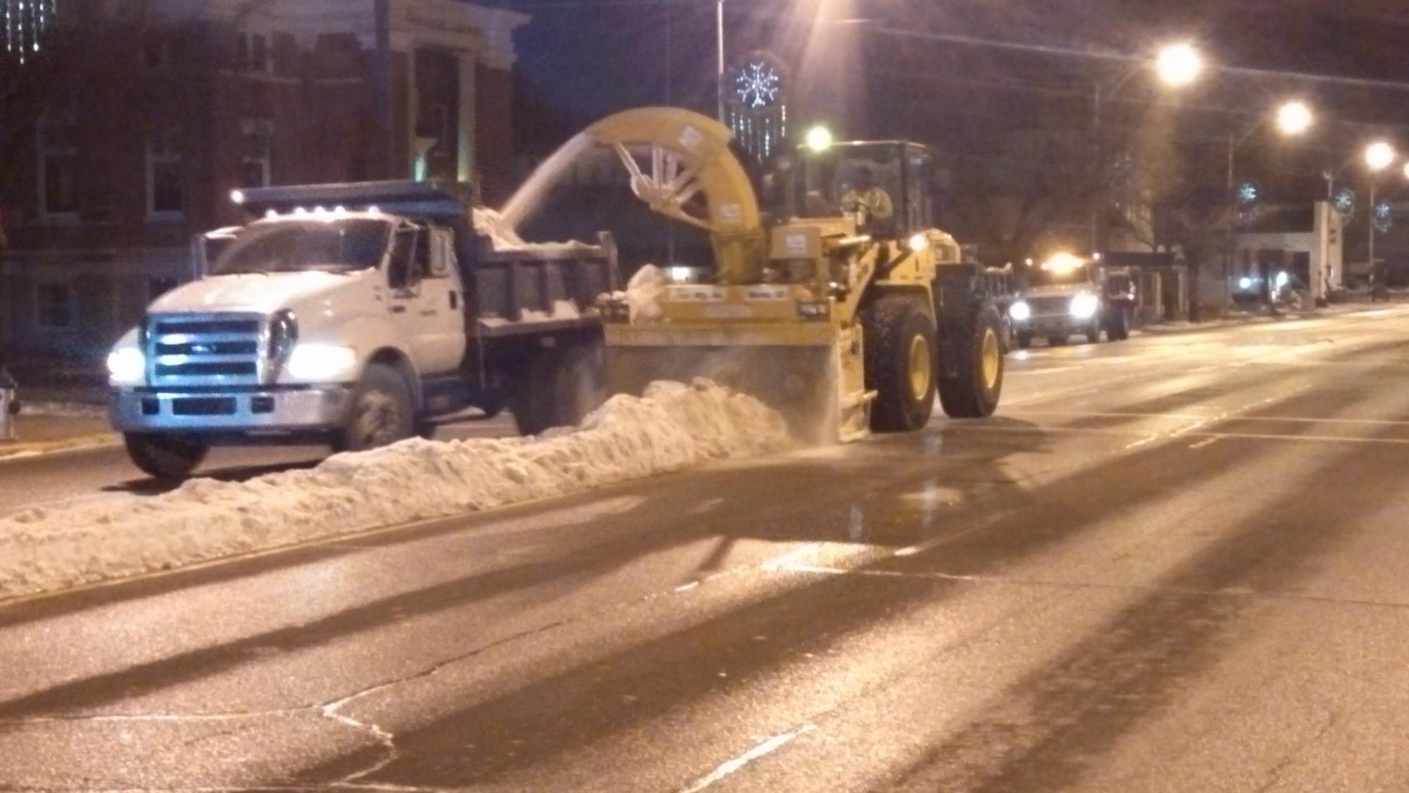 City employees removing snow from a street downtown